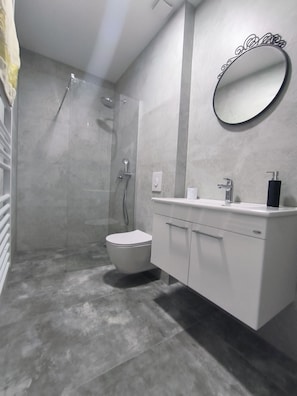 Une salle de bain moderne équipée d’une douche, de toilettes et d’un meuble-lavabo.