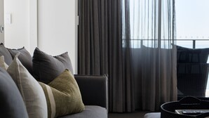 Una sala de estar moderna con un sofá gris, varios cojines y un control remoto sobre una mesita auxiliar.