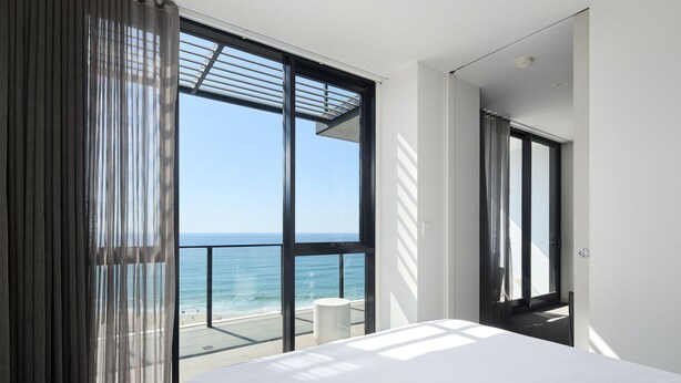 Un dormitorio moderno con ventanas amplias vistas a una playa.