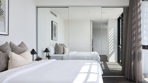 Una habitación de hotel moderna con dos camas, un espejo grande y vistas al exterior.