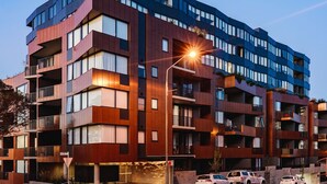 Un immeuble à plusieurs étages, doté de balcons, de grandes fenêtres et d’un lampadaire.