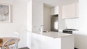 Une cuisine moderne dotée d’un îlot central, d’appareils électroménagers en acier inoxydable et de meubles de rangement en bois clair.