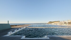 Une piscine avec des couloirs numérotés, une plateforme d’observation et une plage en arrière-plan.