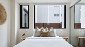 Une chambre à coucher avec un grand lit, deux tables de chevet et trois fenêtres.