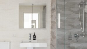 Une salle de bain moderne avec un lavabo blanc, un miroir et une cabine de douche en verre.