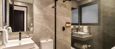 Un baño moderno con ducha de vidrio, lavamanos blanco y retrete.