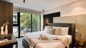 Un dormitorio moderno con una cama grande, una mesita de noche y vistas a zonas verdes.