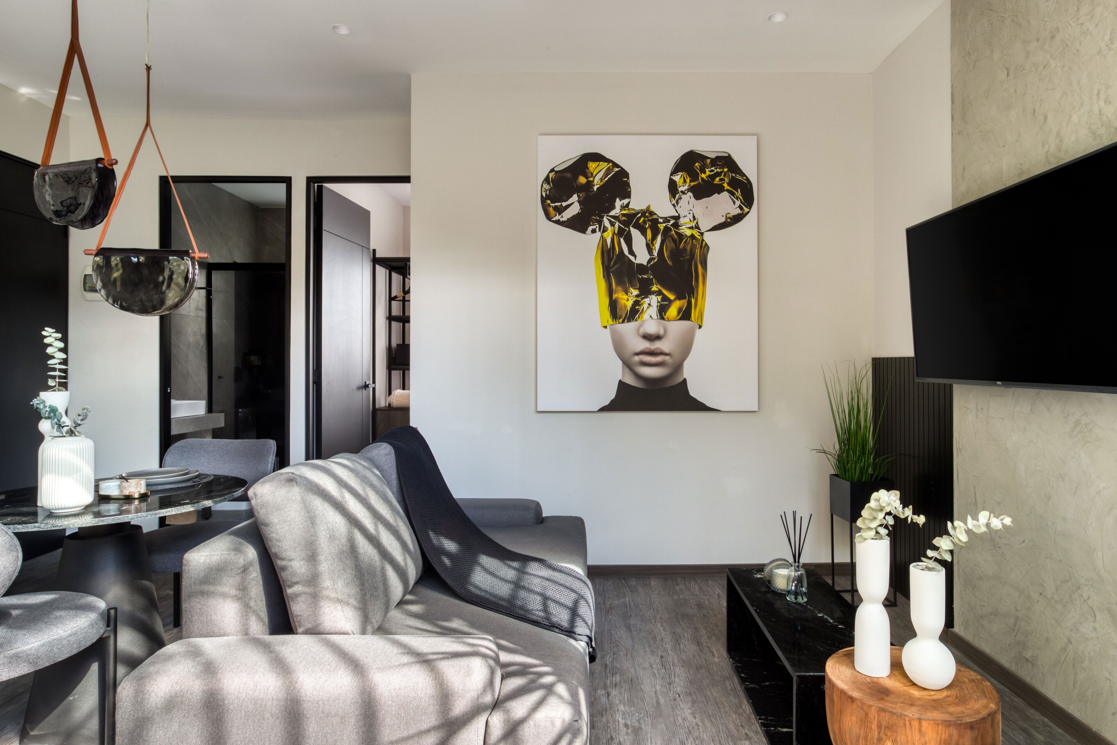 A modern living room with a grey sofa, a black coffee table, and a large abstract painting on the wall.