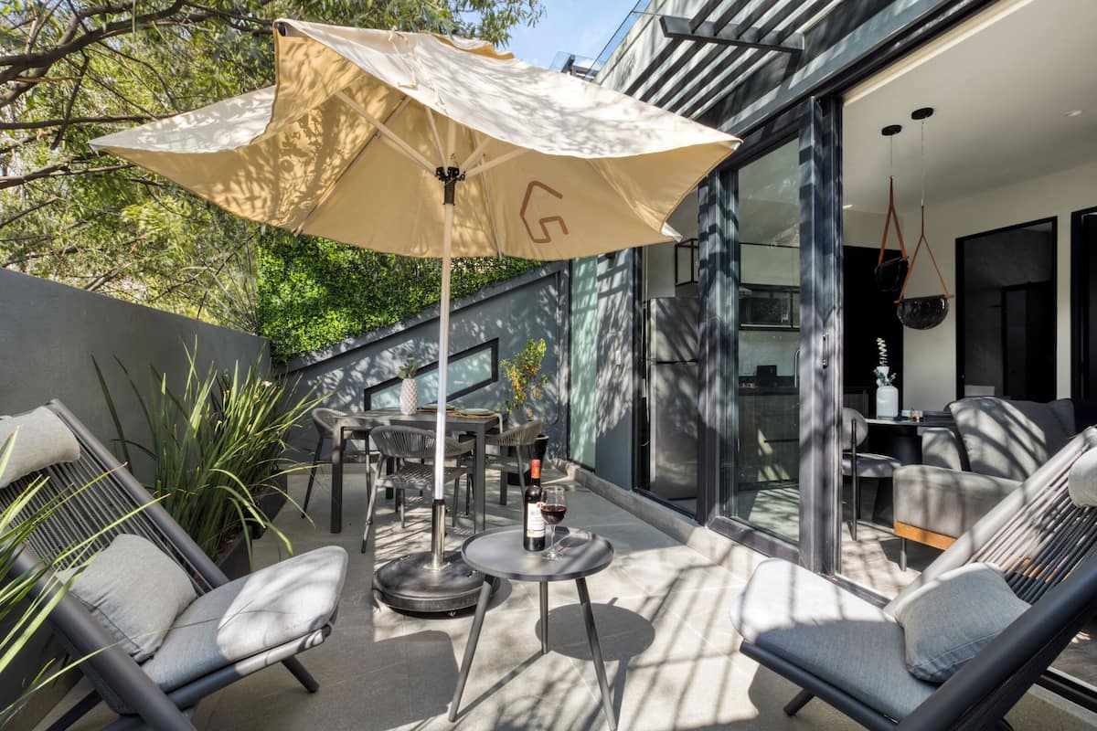 An outdoor patio with a table, chairs, and an umbrella.