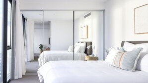 A modern hotel room with a large bed, a bedside table, and a mirror.