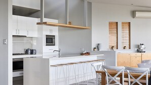 Eine moderne Küche mit weißen Schränken, einer eingebauten Mikrowelle und einer Theke mit Barhocker.