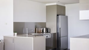 A modern kitchen with a stainless steel refrigerator, a built-in oven, and a sink.