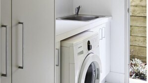 A compact laundry area with a washing machine, a dryer, and a sink.