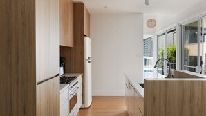 Une cuisine moderne avec des meubles en bois, une cuisinière encastrée et une grande fenêtre offrant une vue sur l’extérieur.