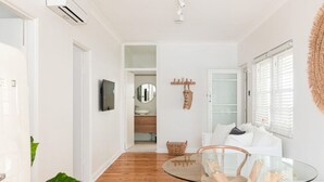 Ein modernes Wohnzimmer mit einem Glastisch, weißen Sofas und Holzboden.