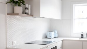 A modern kitchen with white countertops, a toaster, and a potted plant on a shelf. - No 6 ShoalHaven - 1 bed option (Shoal Bay)
