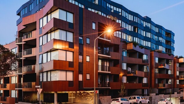 En bygning med flere etager, altaner, store vinduer og en gadelampe.