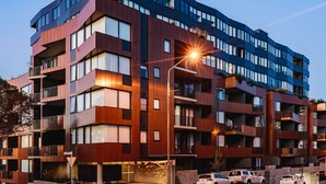 Un immeuble à plusieurs étages, doté de balcons, de grandes fenêtres et d’un lampadaire.