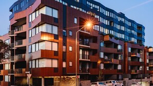 Un edificio de varios pisos con balcones, ventanas amplias y un farol de calle.