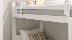 Una litera con colchón y almohadas blancos.