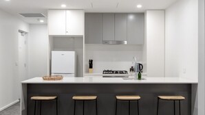 Una cocina moderna con una isla central, cuatro taburetes, un refrigerador y una estufa a gas.