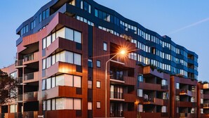Ein mehrstöckiges Gebäude mit Balkonen, großen Fenstern und einer Straßenlaterne.