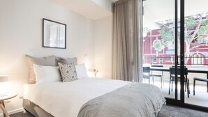 Ein Hotelzimmer mit einem großen Bett, einem gerahmten Bild an der Wand und Blick auf den Außenbalkon.