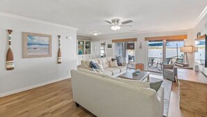 Ein geräumiges Wohnzimmer mit einem großen Sofa, einem Couchtisch und Meerblick durch große Fenster.