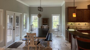A spacious kitchen with a large island, white cabinetry, and a dining area with a long table and chairs. - House in Melrose on Lake Sante Fe (Melrose)