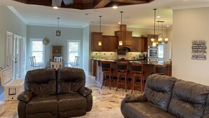 A modern kitchen with wooden cabinets, a central island with bar stools, and pendant lighting. - House in Melrose on Lake Sante Fe (Melrose)