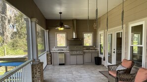 A covered patio with a kitchen area, wicker furniture, and a view of the outdoors. - House in Melrose on Lake Sante Fe (Melrose)