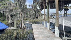 A wooden dock extending over water, supported by stilts, with a boat docked on the right. - House in Melrose on Lake Sante Fe (Melrose)