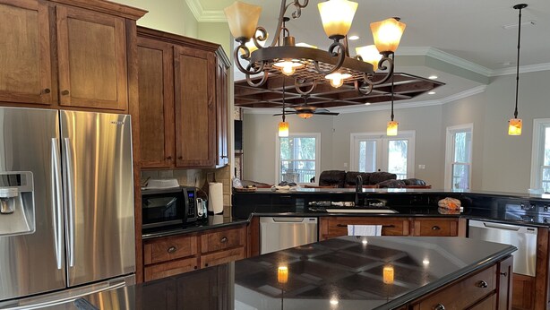 A modern kitchen with stainless steel appliances, wooden cabinets, and a central island. - House in Melrose on Lake Sante Fe (Melrose)
