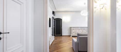 A hallway with a wooden floor, white walls, and a black door.