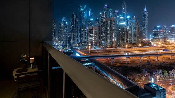 Vista nocturna de un horizonte urbano con edificios iluminados y una autopista.