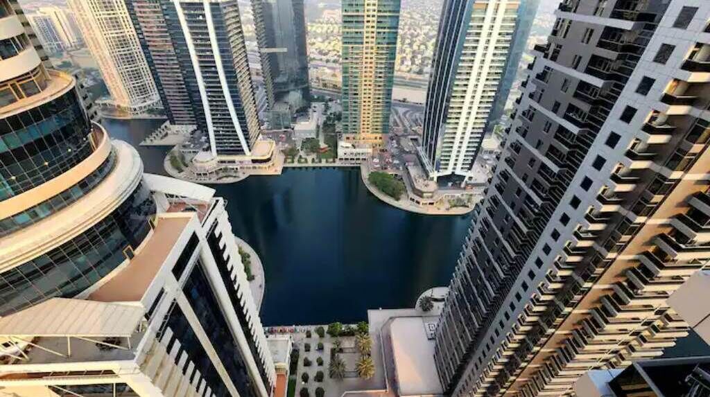 Um edifício alto com vista para um corpo d'água e outros edifícios.