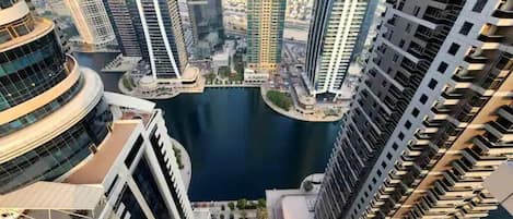A high-rise building with a view of a water body and other buildings.
