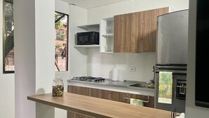 A modern kitchen with a built-in microwave, a stainless steel refrigerator, and wooden cabinets. - Exclusivo Apartamento Privado Zona Rosa Sabaneta (Sabaneta)