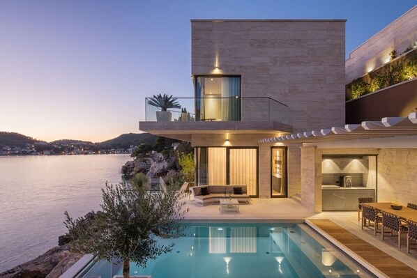 A modern house with a pool, a balcony, and a view of the sea.