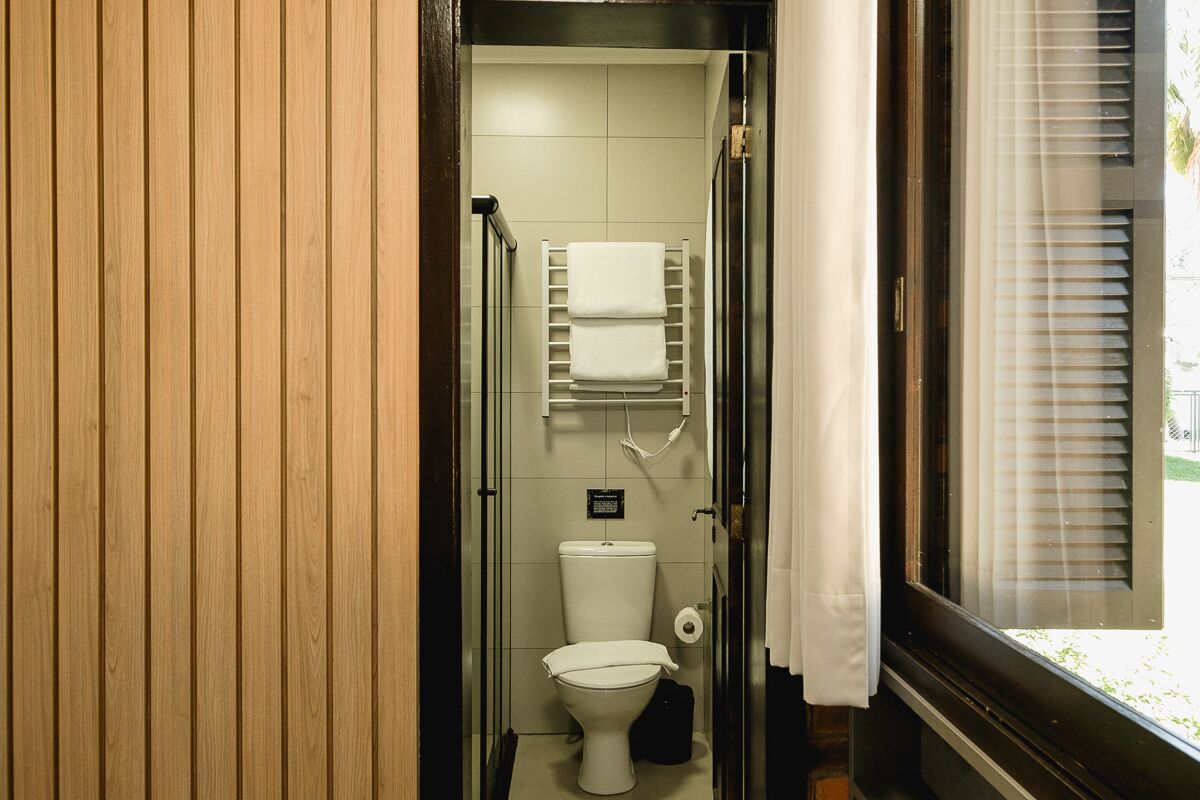 Un baño pequeño con inodoro, toallero y ventana con persianas.