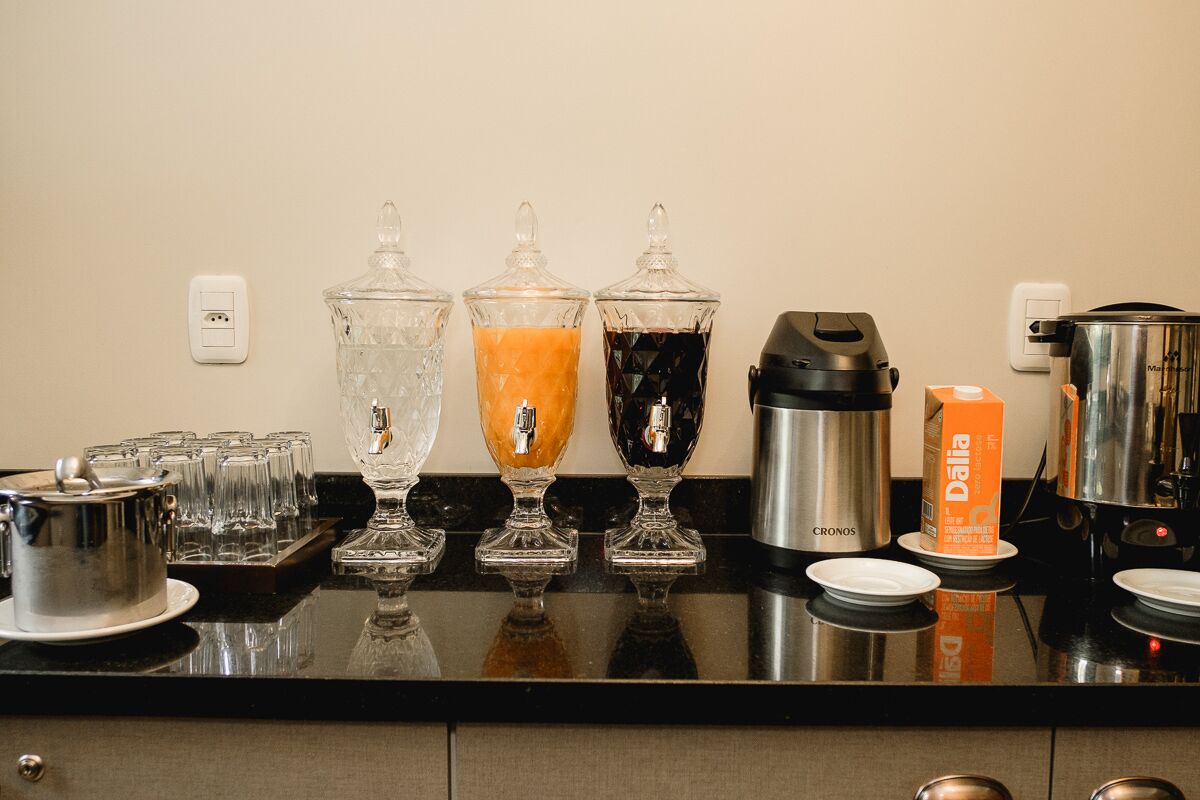 Una encimera de cocina con una cafetera, un termo y un dispensador de café con varias tazas.