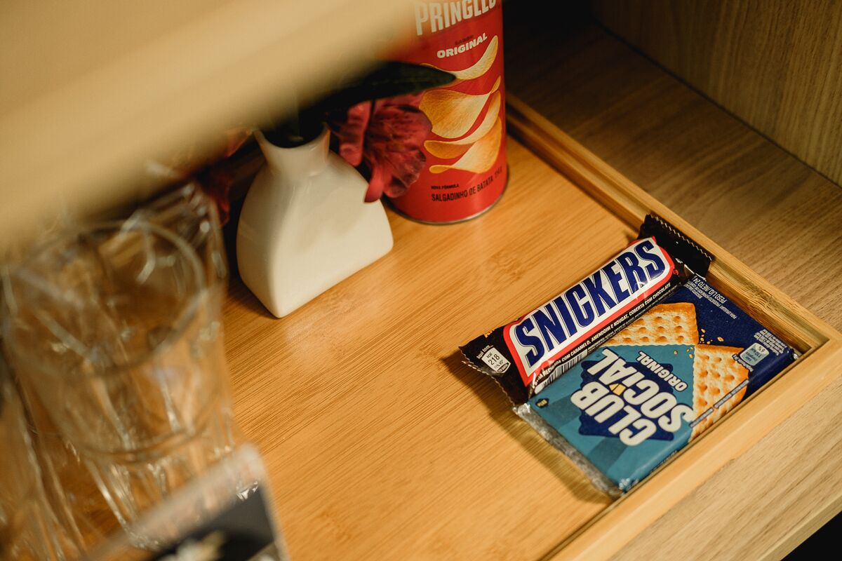 Una bandeja de madera con una barra de Snickers y una lata de Pringles.