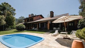 A house with a swimming pool, patio furniture, and a large umbrella.