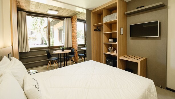 A modern hotel room with a large bed, a desk, and a TV.