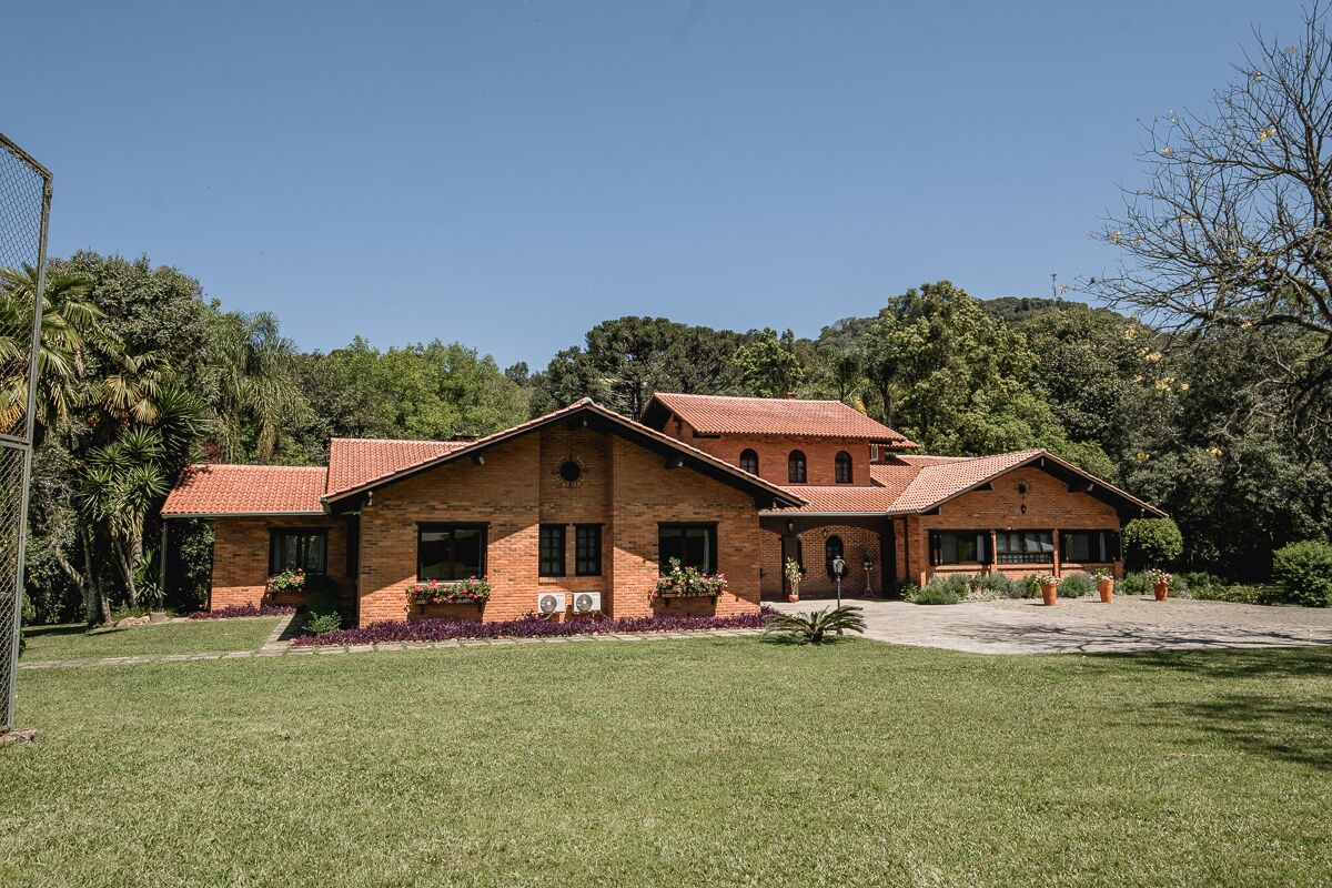 A two-story brick house with a red-tiled roof, surrounded by a well-maintained lawn and trees.