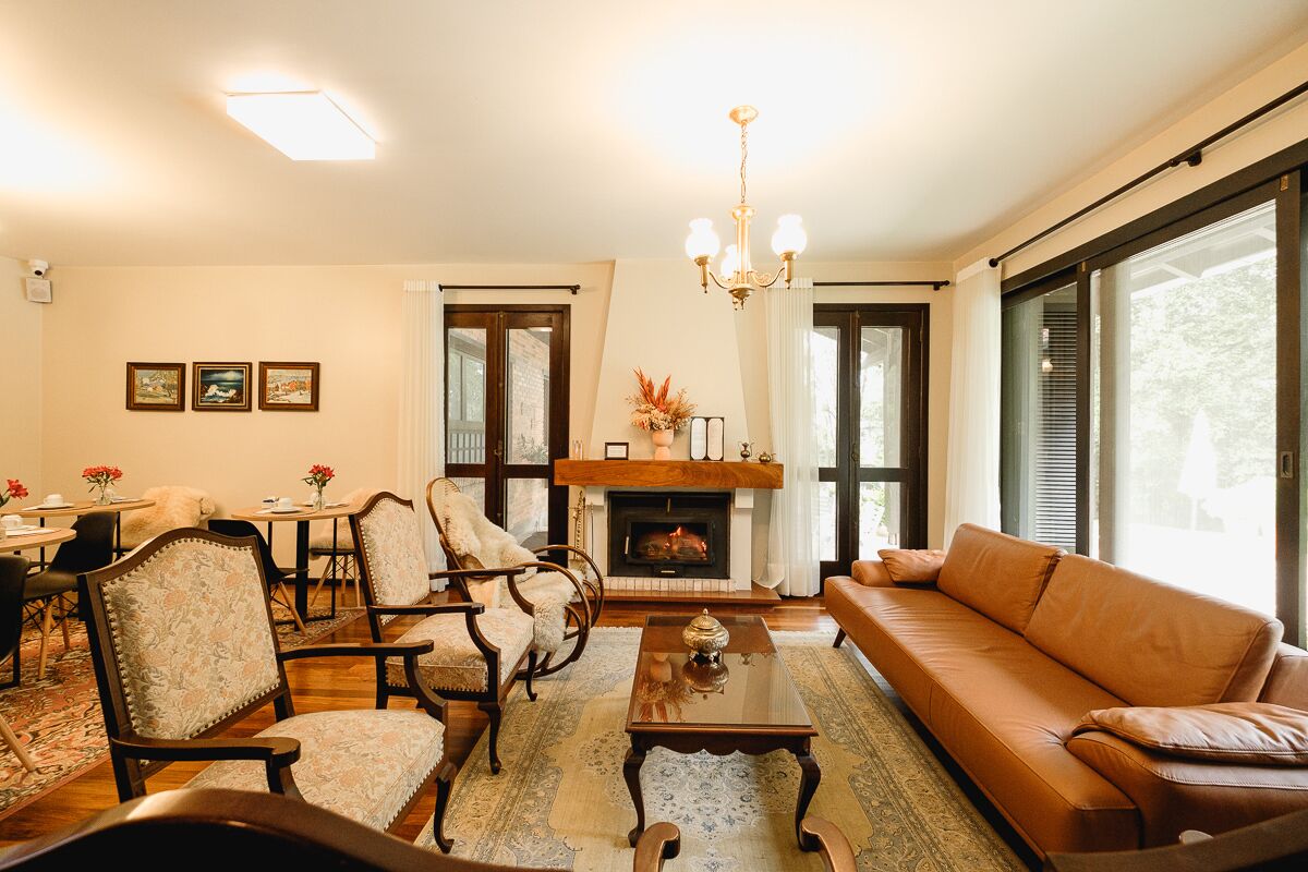 Una sala de estar bien iluminada con chimenea, un sofá y un comedor con sillas y una mesa.