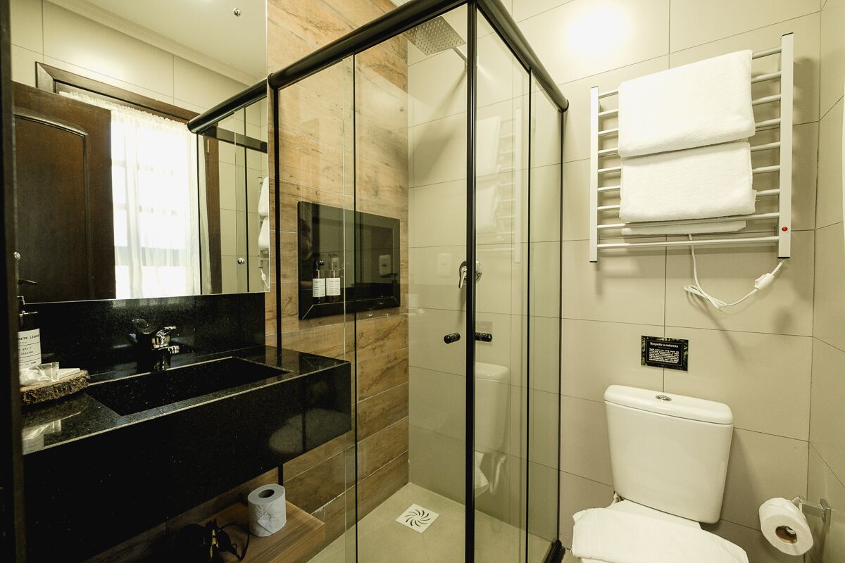 Een moderne badkamer met een douche met glazen wand, een zwart wastafel en een wit toilet.