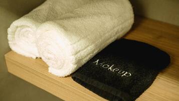 A wooden shelf with two white towels and a black towel with the word "Mokeyup" on it.