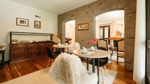 A dining area with a brick wall, wooden cabinets, and a round table with chairs.