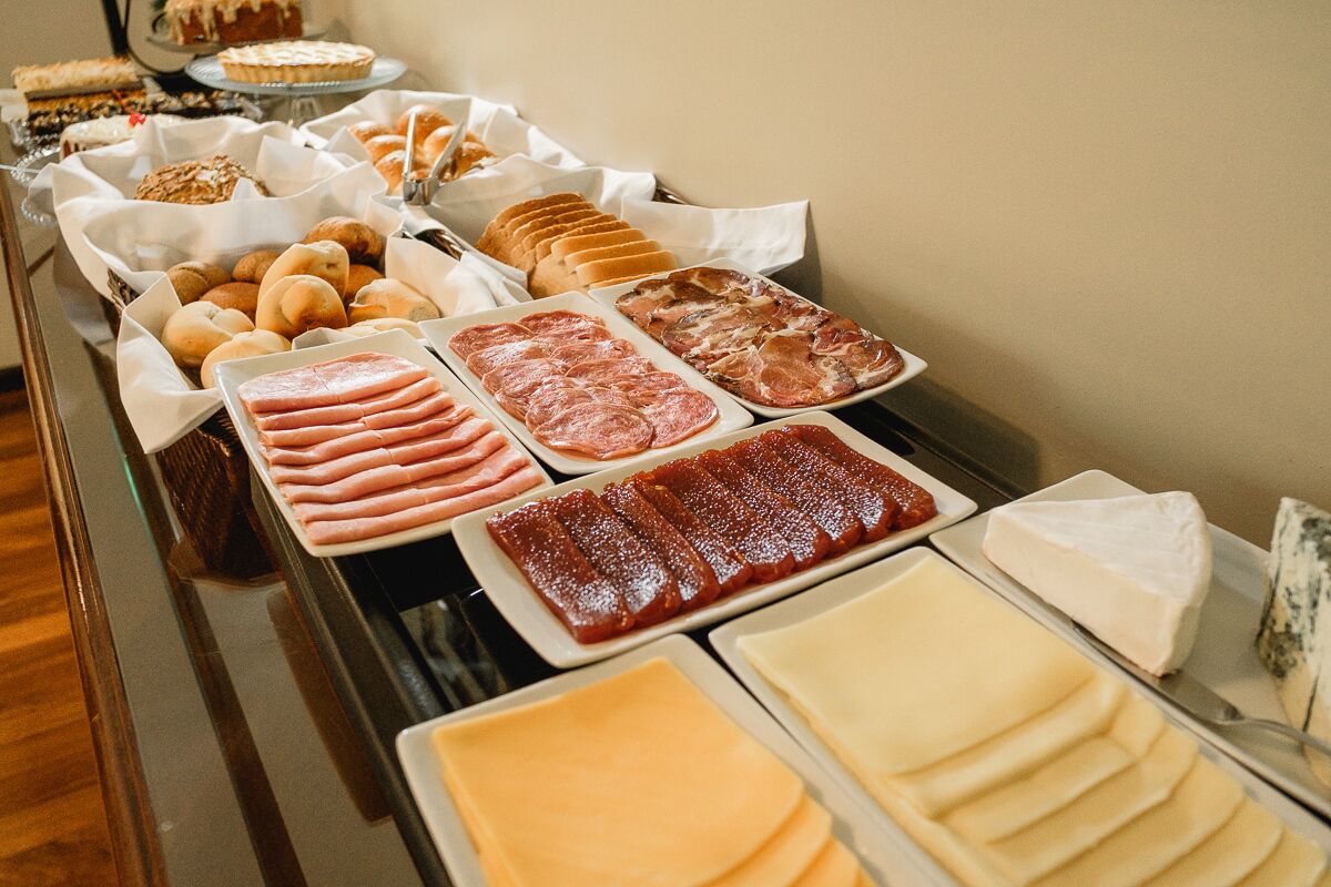 A buffet table with various food items including meats, cheeses, and pastries.